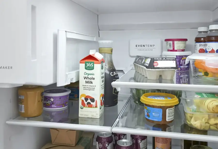 The image shows a refrigerator filled with various food items. The refrigerator has a shelf with a carton of organic whole milk, a bottle of juice, and a carton of eggs. There are also several other bottles and containers of food, including a bottle of juice, a bottle of soda, and a bottle of sauce. The refrigerator is stocked with a variety of items, making it a well-stocked and functional appliance.