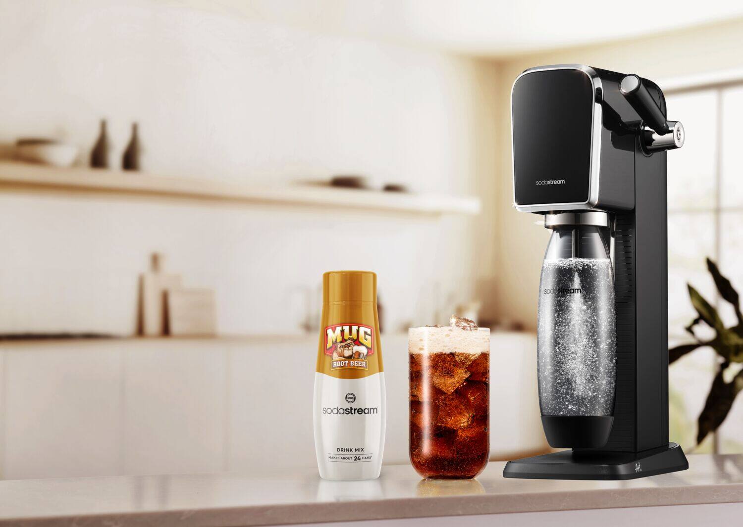 The image features a counter with a SodaStream machine, a bottle of root beer, and a glass of root beer. The machine is placed next to a bottle of root beer, and the glass is filled with the root beer. The counter also has a potted plant nearby, adding a touch of greenery to the scene.
