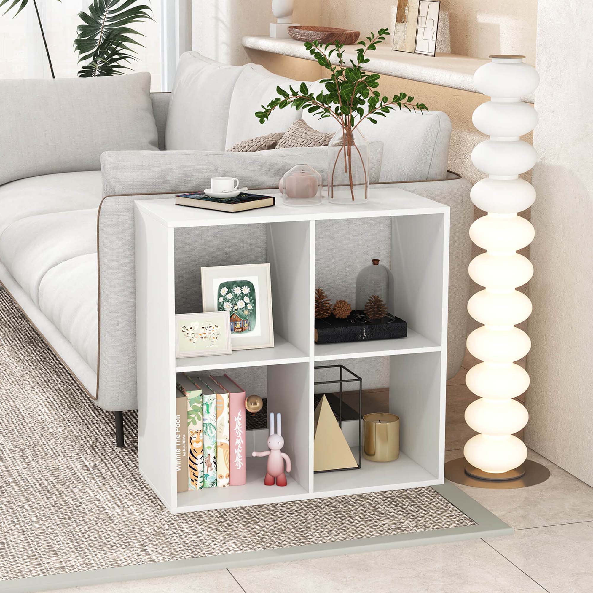 The image shows a living room with a white couch, a coffee table, and a bookshelf. The bookshelf is filled with various items, including books, a vase, and a potted plant. The coffee table has a cup, a bowl, and a vase on it. The living room is well-decorated and organized, creating a comfortable and inviting atmosphere.