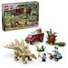 The image features a Lego set with a dinosaur theme, including a T-Rex and a truck. The set contains 420 pieces and is designed for children aged 6 and above. The box also includes a warning about choking hazards. The set is displayed on a table, showcasing the various dinosaur and vehicle figures.