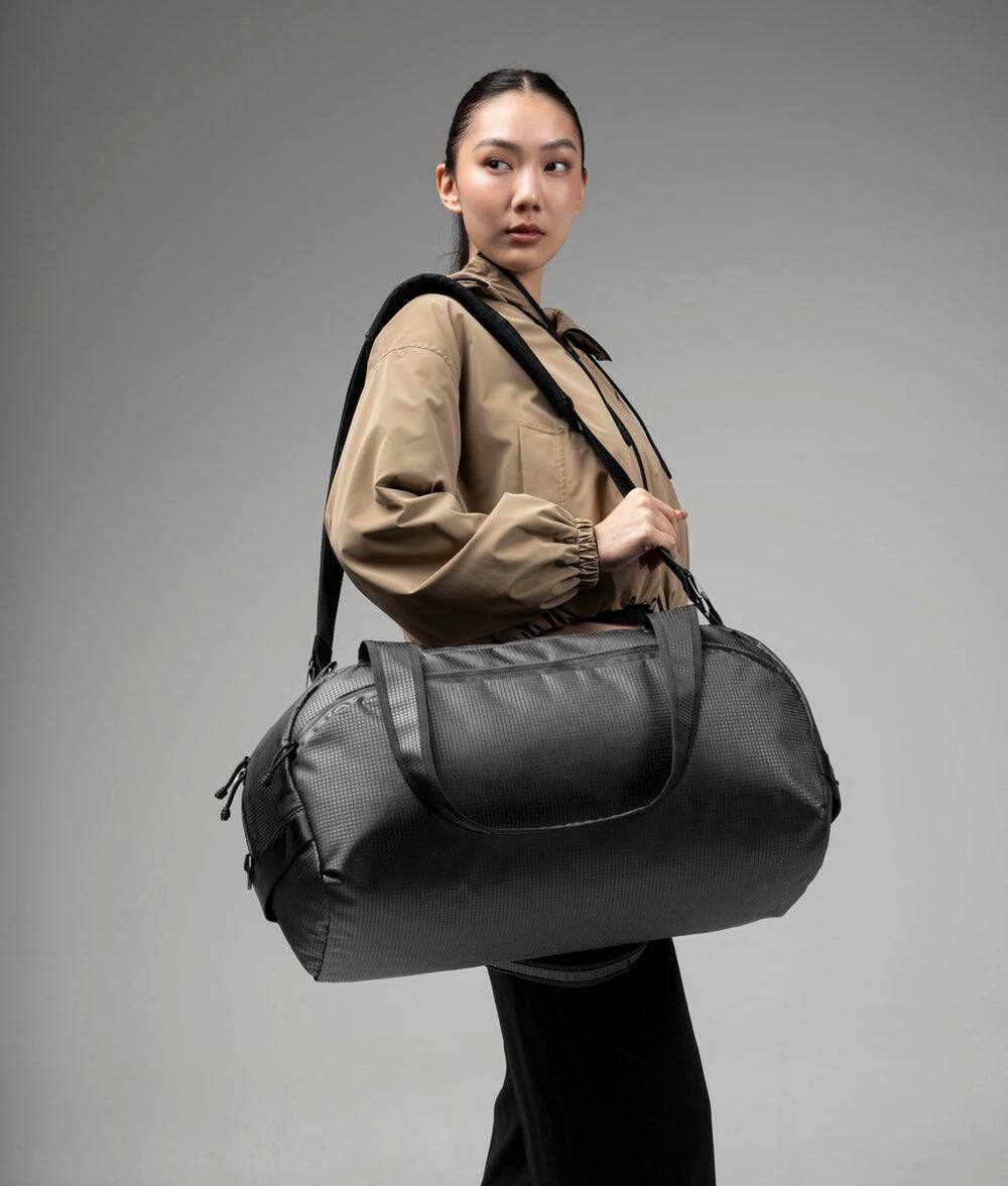 Left. ALPAKA - 35L Lightweight Duffel Bag for Gym, Weekend Trips & Carry-On Travel, Momentum Duffel, Weather-Resistant - Axodyne hybrid Black.