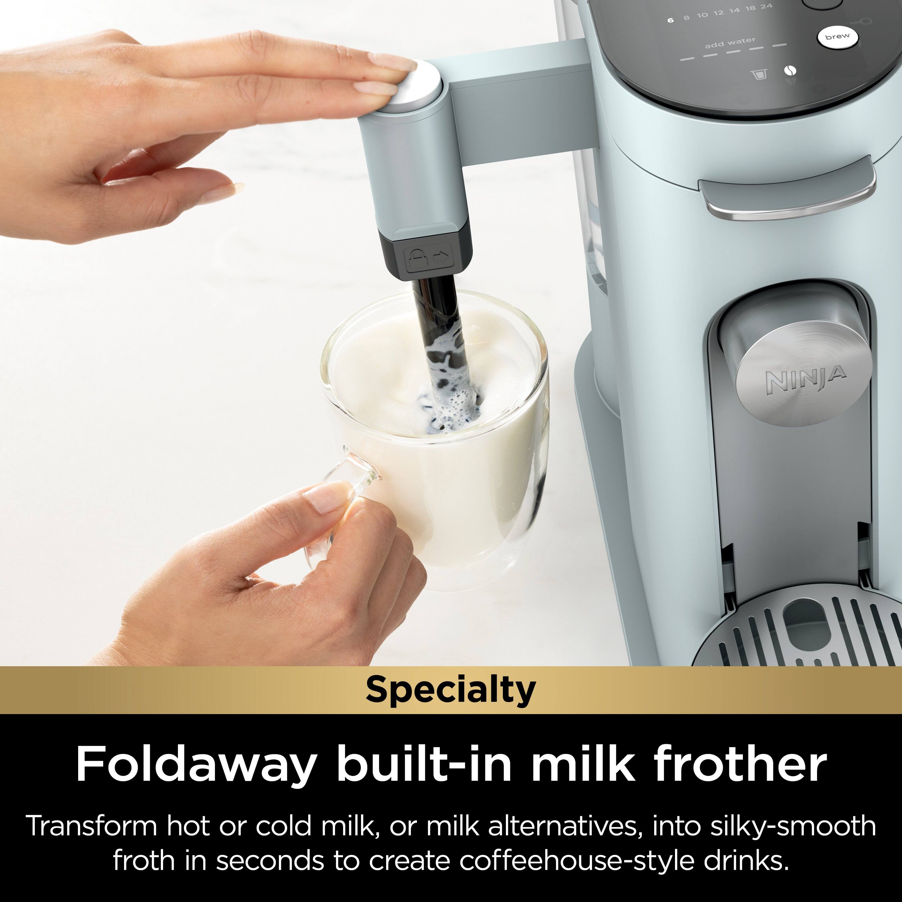 The image features a person pouring milk into a cup using a Ninja Specialty Foldaway built-in milk frother. The frother is designed to transform hot or cold milk, or milk alternatives, into silky-smooth froth in seconds, creating coffeehouse-style drinks. This appliance is a convenient and efficient way to prepare delicious beverages at home.