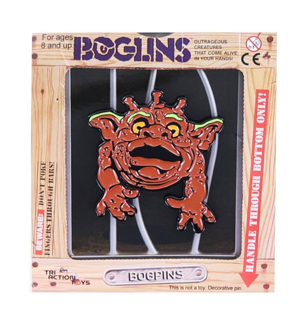 For ages 8 and up  
BOGINS  
OUTRAGEOUS CREATURES THAT COME ALIVE IN YOUR HANDS!  

BEWARE: FINGERS THROUGH BOTTOM HANDLE!  
HANDLE THROUGH BOTTOM BUTTON ONLY!  

This is not a toy. Decorative pin.  

TRI ACTION TOYS