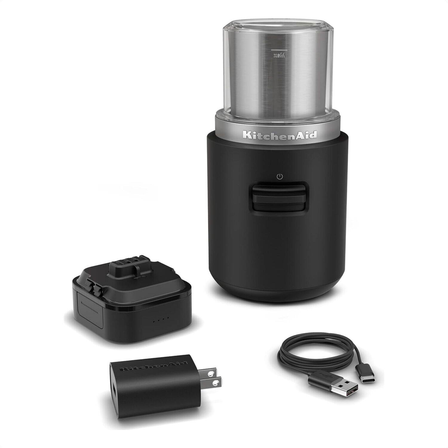 KitchenAid is a brand of kitchen appliances, including mixers and blenders. The image shows a black KitchenAid blender with a silver top, along with a black power adapter and a black cord. The blender is designed to be portable and easy to use, making it a convenient addition to any kitchen.