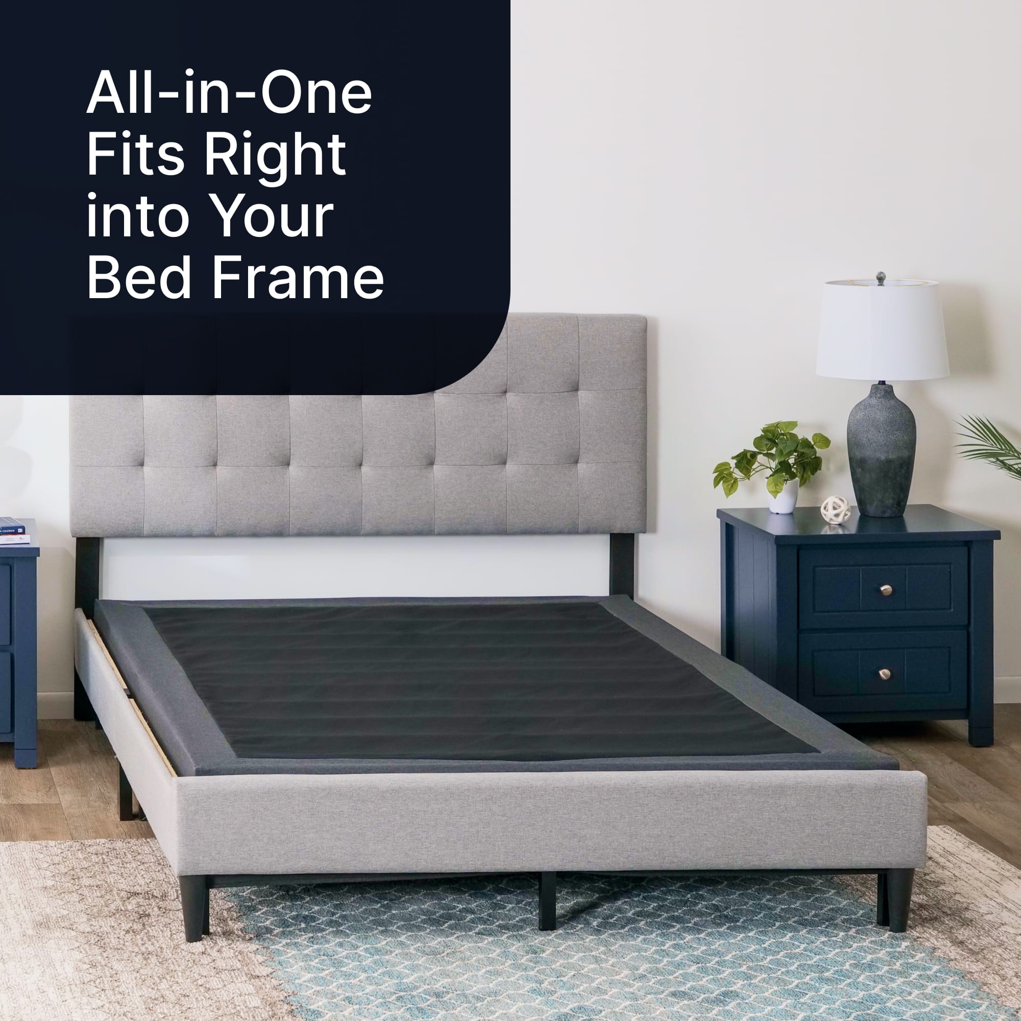 The image features a bed with a black mattress and a headboard. The bed is placed on a carpeted floor, and there is a nightstand next to it. The headline "All-in-One Fits Right into Your Bed Frame" suggests that the bed frame and mattress are designed to fit together seamlessly, providing a convenient and space-saving solution for bedroom furniture.