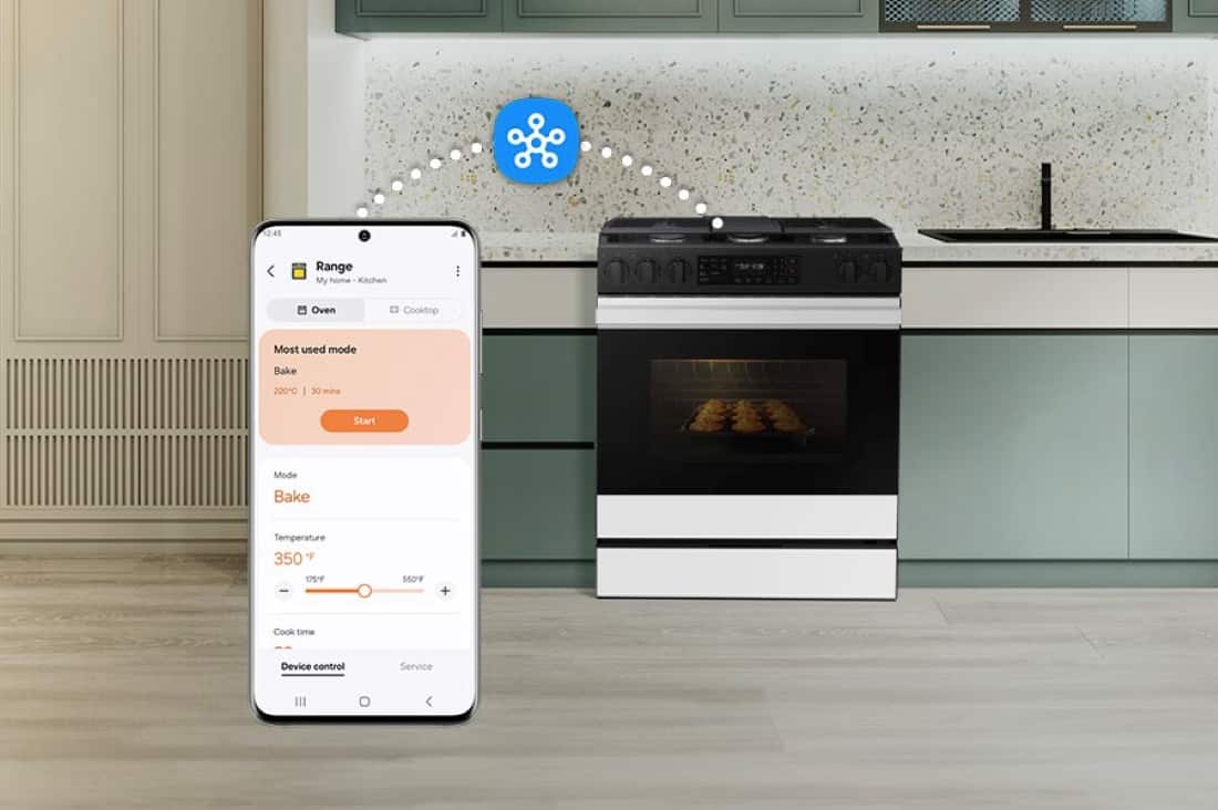 The image shows a kitchen with a stove and oven, and a cell phone is placed above the oven. The text on the image reads "12:45 Range My home Kitchen Oven Cooktop Most used mode Bake 220C 125/ - 560F + Cook time Device control Service." This text suggests that the oven is being used for baking at a temperature of 220 degrees Celsius, and the cooking time is being monitored by the device control service. The cell phone may be used to control the oven remotely or to receive notifications about the cooking progress.