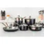 The image features a kitchen counter with a variety of cookware, including several pots and pans. There are three pots and three pans arranged on the counter, with one large pot and two smaller pots on the left side, and two large pans and one smaller pan on the right side. The cookware is made of stainless steel, and they are all black in color. The counter also has a few oranges and a bottle placed on it. The kitchen is equipped with an oven, and there are multiple knives displayed in the background, indicating that it is a well-equipped cooking space.