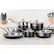 The image features a kitchen counter with a variety of cookware, including several pots and pans. There are three pots and three pans arranged on the counter, with one large pot and two smaller pots on the left side, and two large pans and one smaller pan on the right side. The cookware is made of stainless steel, and they are all black in color. The counter also has a few oranges and a bottle placed on it. The kitchen is equipped with an oven, and there are multiple knives displayed in the background, indicating that it is a well-equipped cooking space.