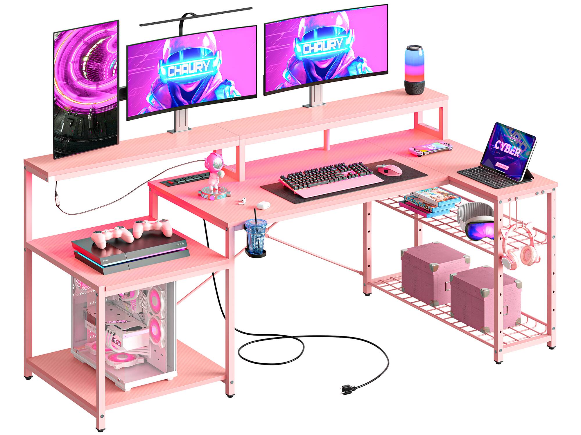 The image features a desk with a laptop, keyboard, and mouse on it. The desk is pink and has a shelf underneath it. There are also two monitors on the desk, and a cell phone is placed nearby. The desk is set up for a person to work on, with all the necessary equipment for a productive workspace.