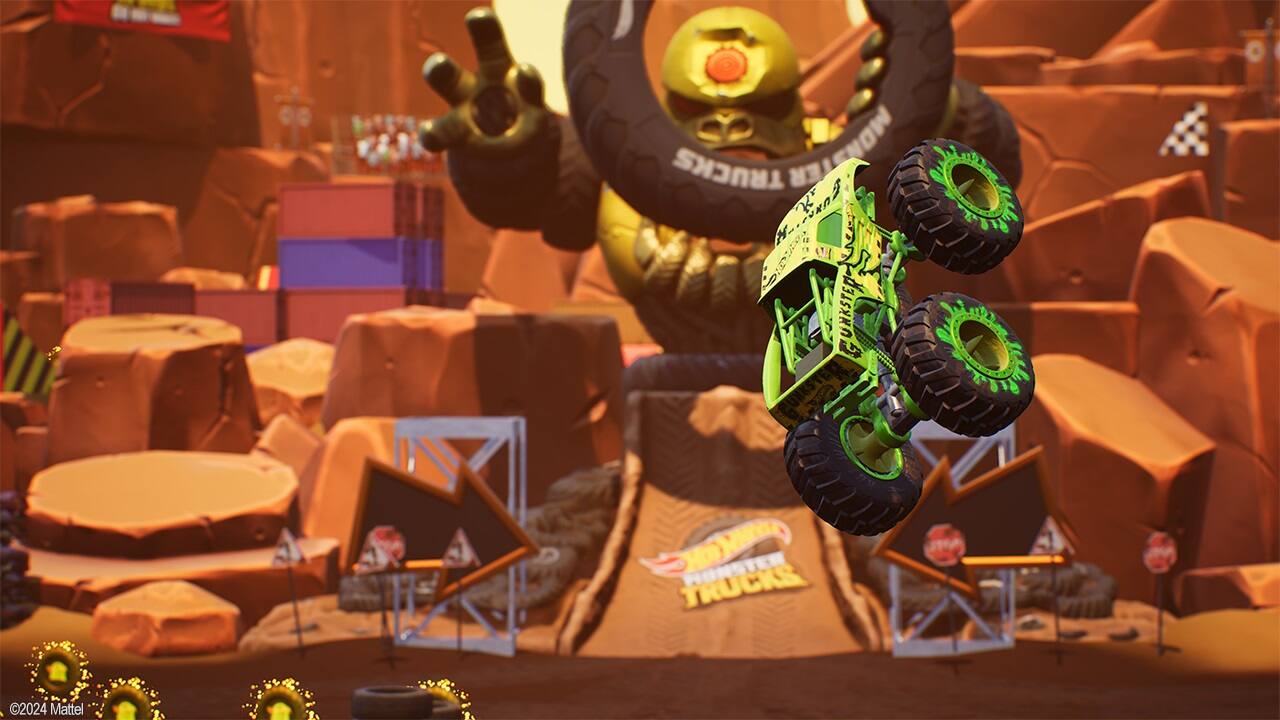 The image features a green monster truck with large wheels, jumping over a ramp. The truck is in mid-air, performing a stunt. The scene is set in a rocky area, with a giant statue in the background. The text on the image reads "TRUCKS MONSTER 2 NAG SDut M O  UNKSTED G  TRUCKS 2024 Mattel."
