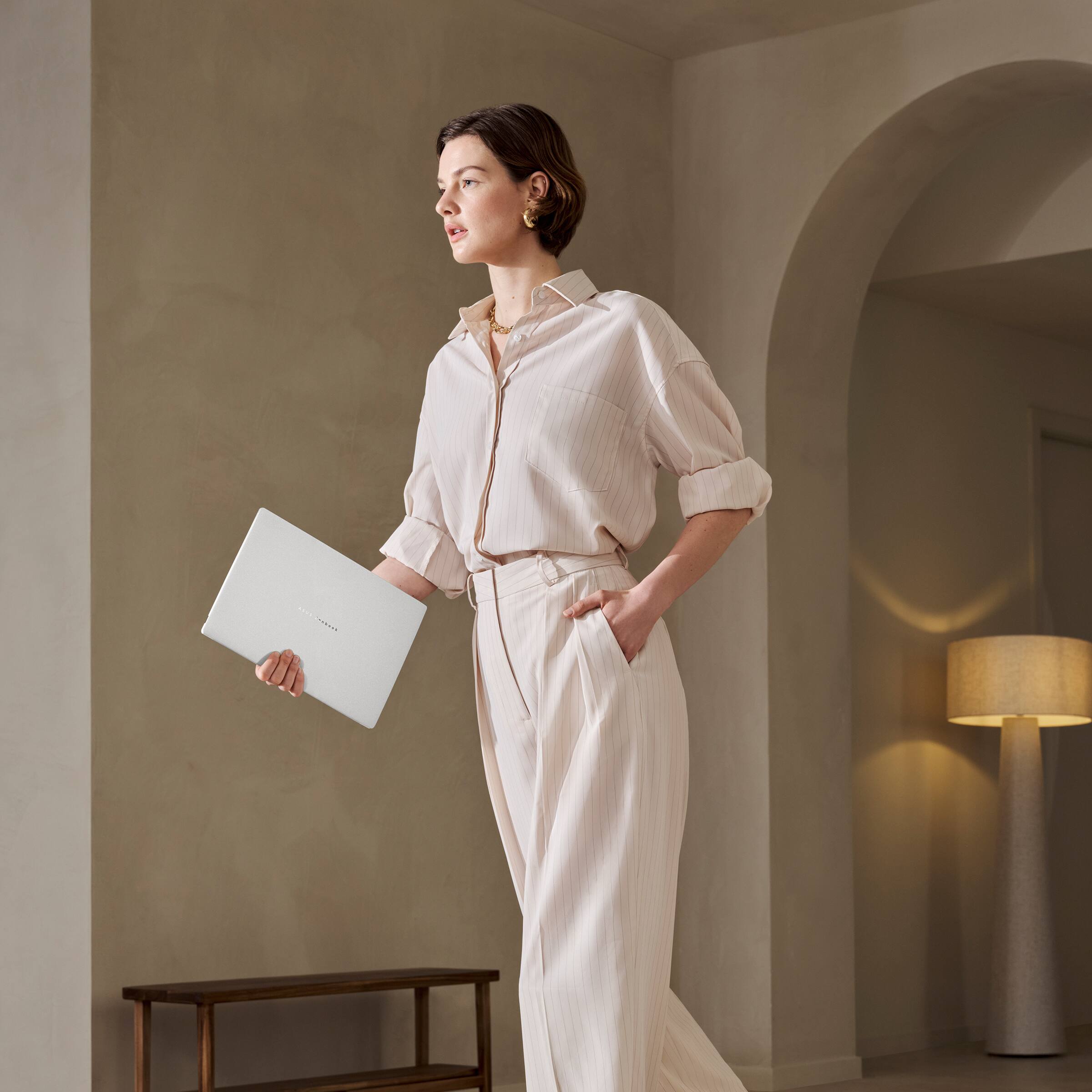 The image does not contain any text to group or correct. It shows a person standing in a room, holding a laptop.