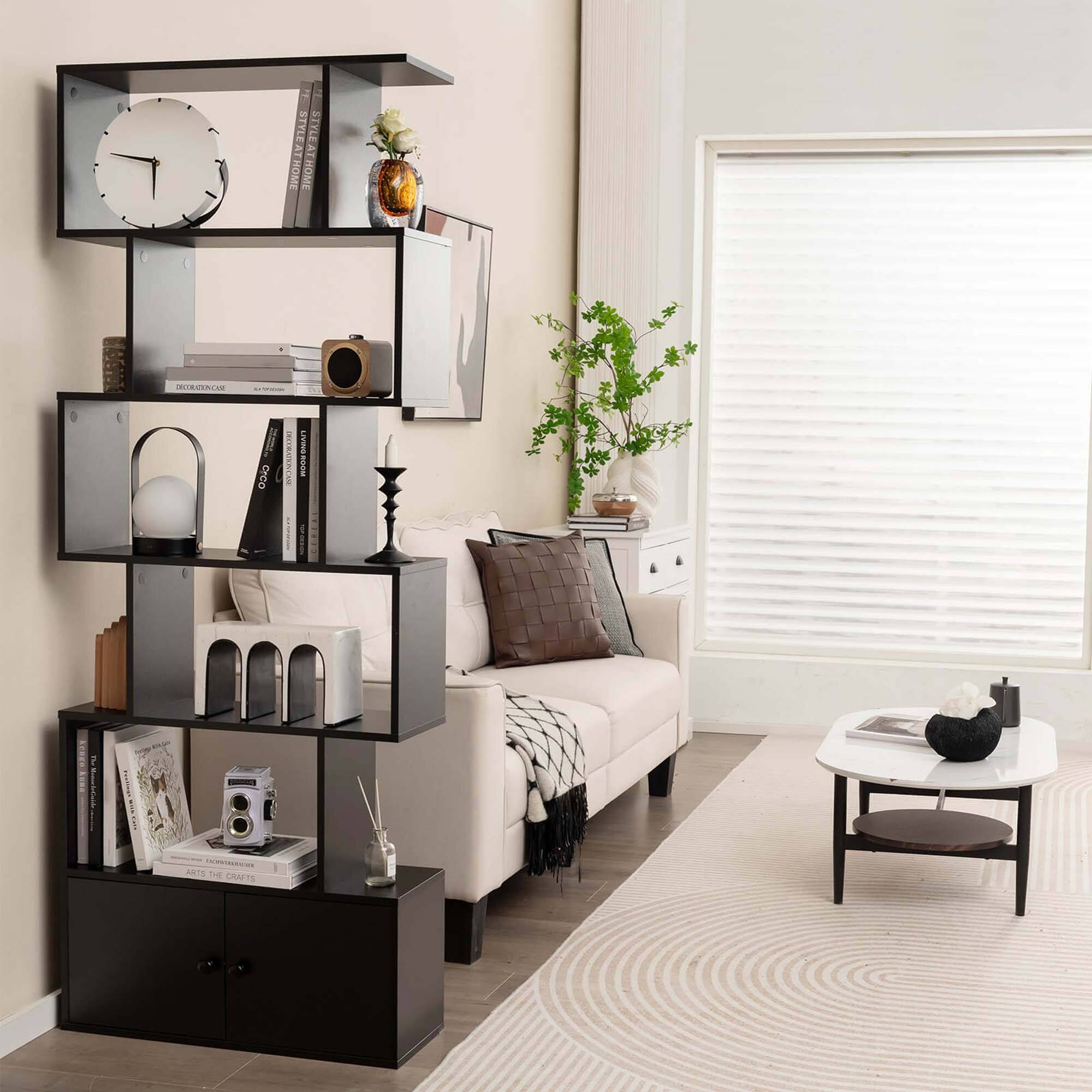 The image features a living room with a black shelf unit and a white couch. The shelf unit is filled with various items, including books, a clock, and a vase. The room also has a potted plant, a table, and a chair. The overall style of the room is modern and well-organized.