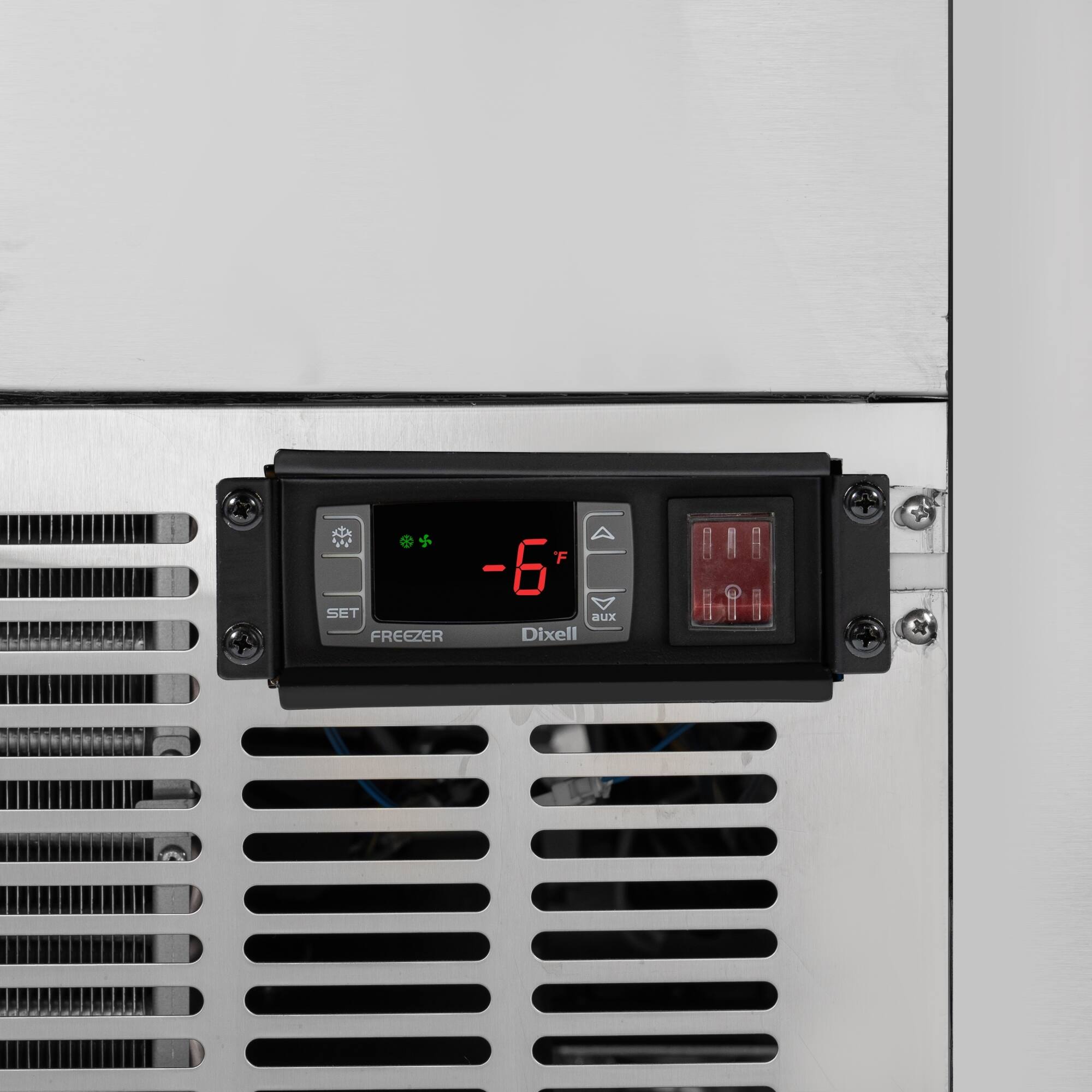 The text on the image reads "F -6 SET aux FREEZER Dixell." This text is likely related to the function of the device, which is a freezer control panel. The panel is attached to a metal surface, possibly a refrigerator or freezer. The "F -6 SET" suggests that the device is set to a temperature of -6 degrees Celsius, which is quite cold. The "aux" in the text might indicate that the device is an auxiliary control panel for the freezer. The "Dixell" could be the brand or manufacturer of the device.