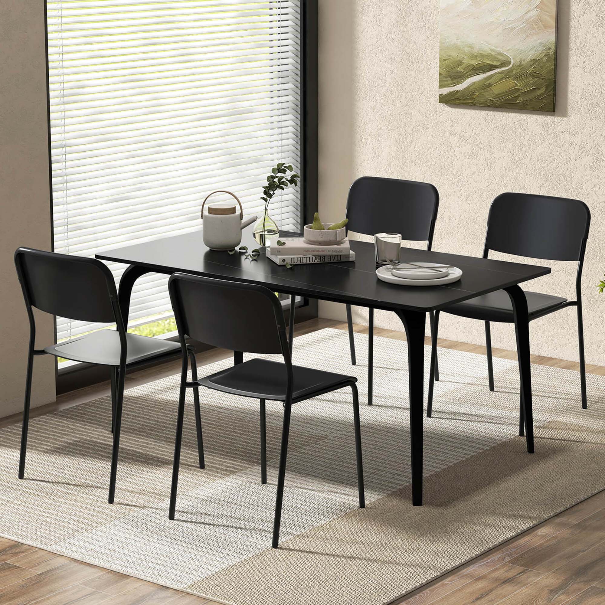I'm sorry, but I cannot group or correct the text "MEDIEUL 7l LIVE" as it does not appear to be related to the image. The image shows a black dining table with four chairs, a vase, and a potted plant. The table is set with plates, cups, and a book. The table is placed in front of a window, and there is a rug underneath the table.
