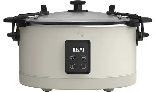 The image features a white Bella Pro slow cooker with a digital display. The display shows the time of 10:29. The cooker is designed to be used with a smartphone, allowing users to control and monitor their cooking from their devices. The cooker is placed on a countertop, ready for use.
