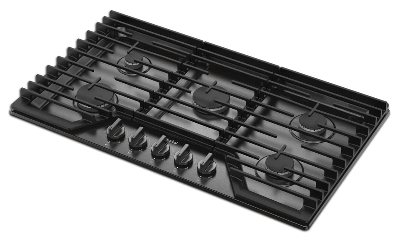 The image features a black stove top with six burners. The burners are arranged in a square pattern, with three burners on each side. The stove top is placed on a white background, which highlights the burners and their arrangement. The stove top appears to be a modern and sleek design, suitable for various cooking needs.