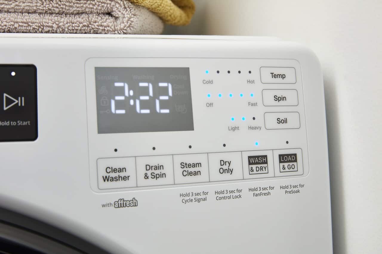The image shows a washer and dryer combo with a digital display. The display shows the time, which is currently 2:22. The buttons on the machine include options for washing, drying, and spinning. There is also a "Clean Drain Washer & Spin" button, as well as a "FanFresh Control" button. The machine also has a "Load & Go" button and a "PreSoak" button.