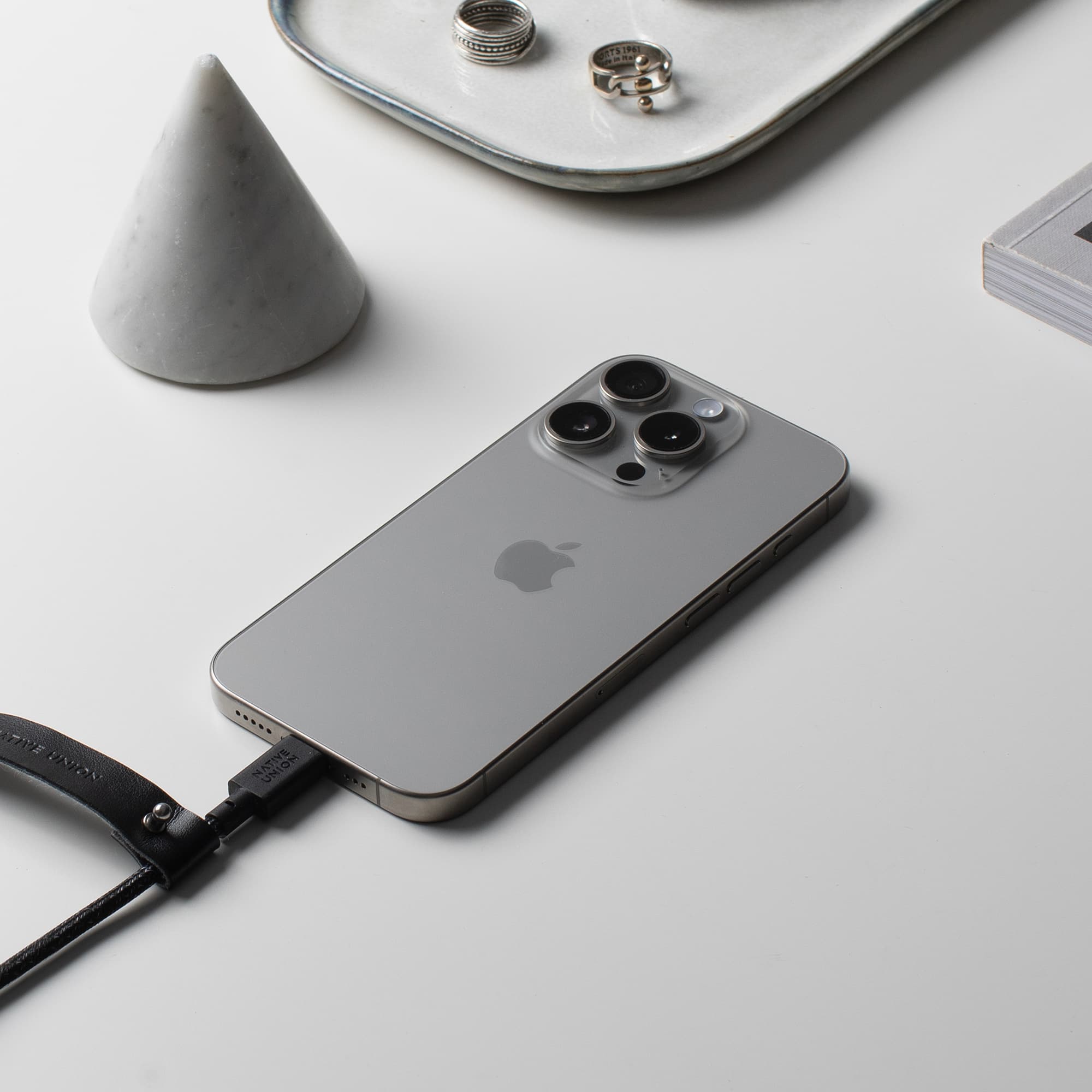 Apple iPhone with a black leather case and a charger plugged in.