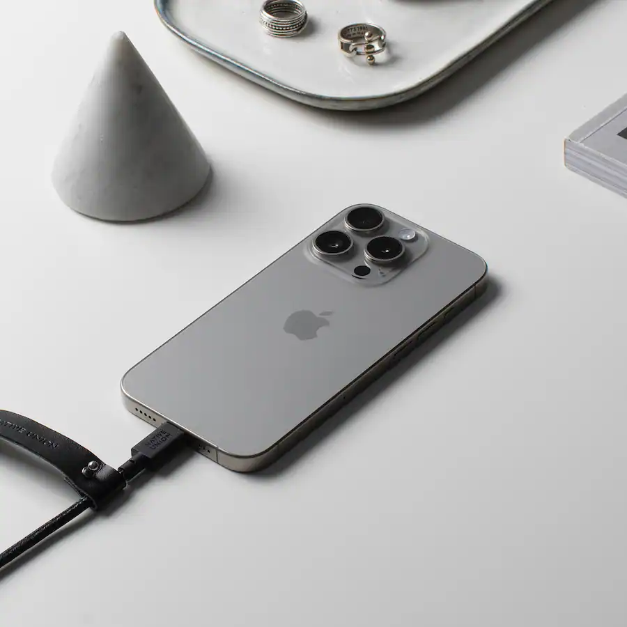 iPhone de Apple con funda de cuero negro y cargador enchufado.