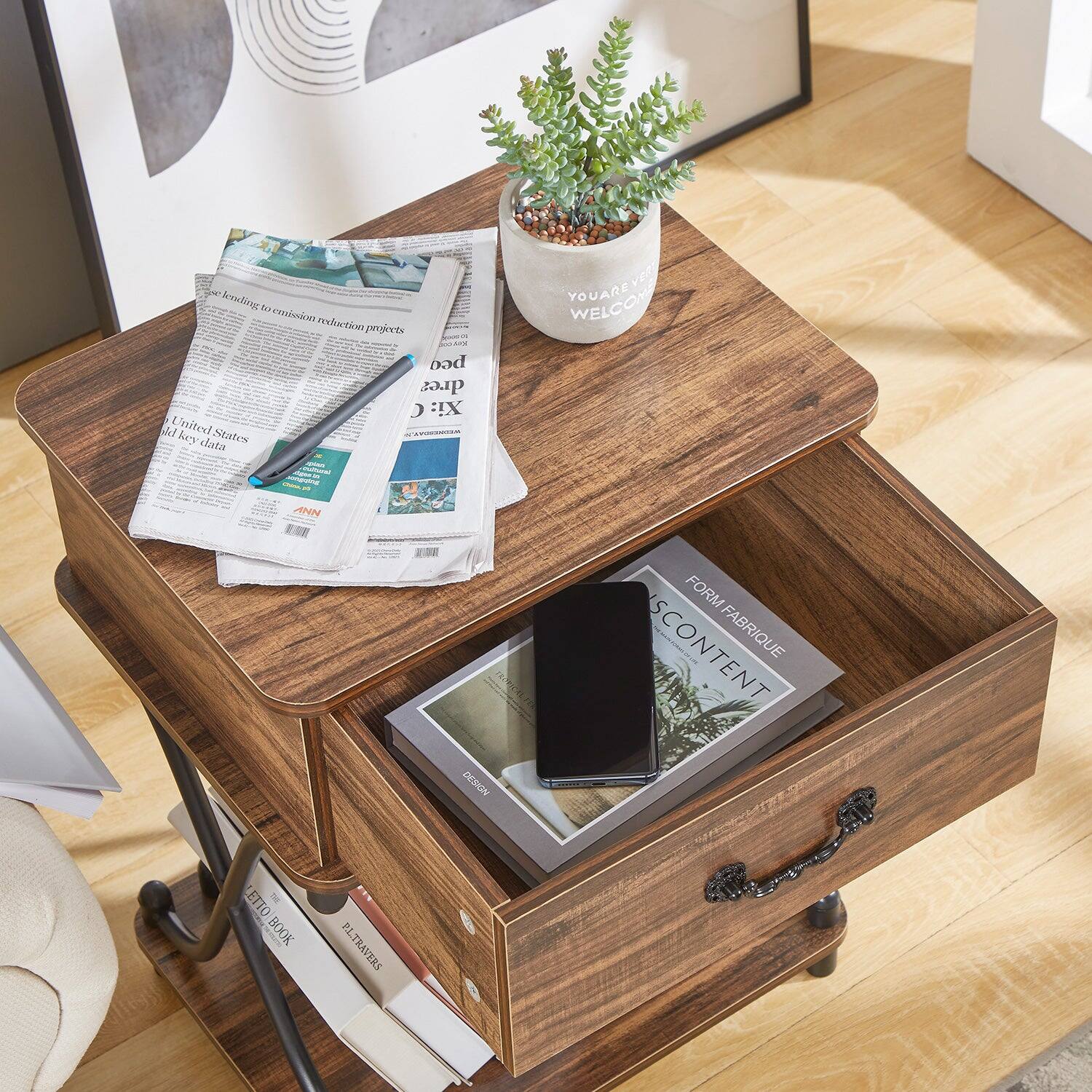 Sure, here is the corrected and grouped text from the image:

---

**Top of the Image:**
- "YOU ARE WELCOME"

**On the Newspaper:**
- "pass lending to emission reduction projects"
- "United States"
- "gold key data"

**On the Book in the Drawer:**
- "FORM FABRIQUE"
- "CONTENT"

**On the Potted Plant:**
- "YOU ARE WELCOME"

**On the Books in the Drawer:**
- "ZERO BOOK"
- "PL TRAVES"

---