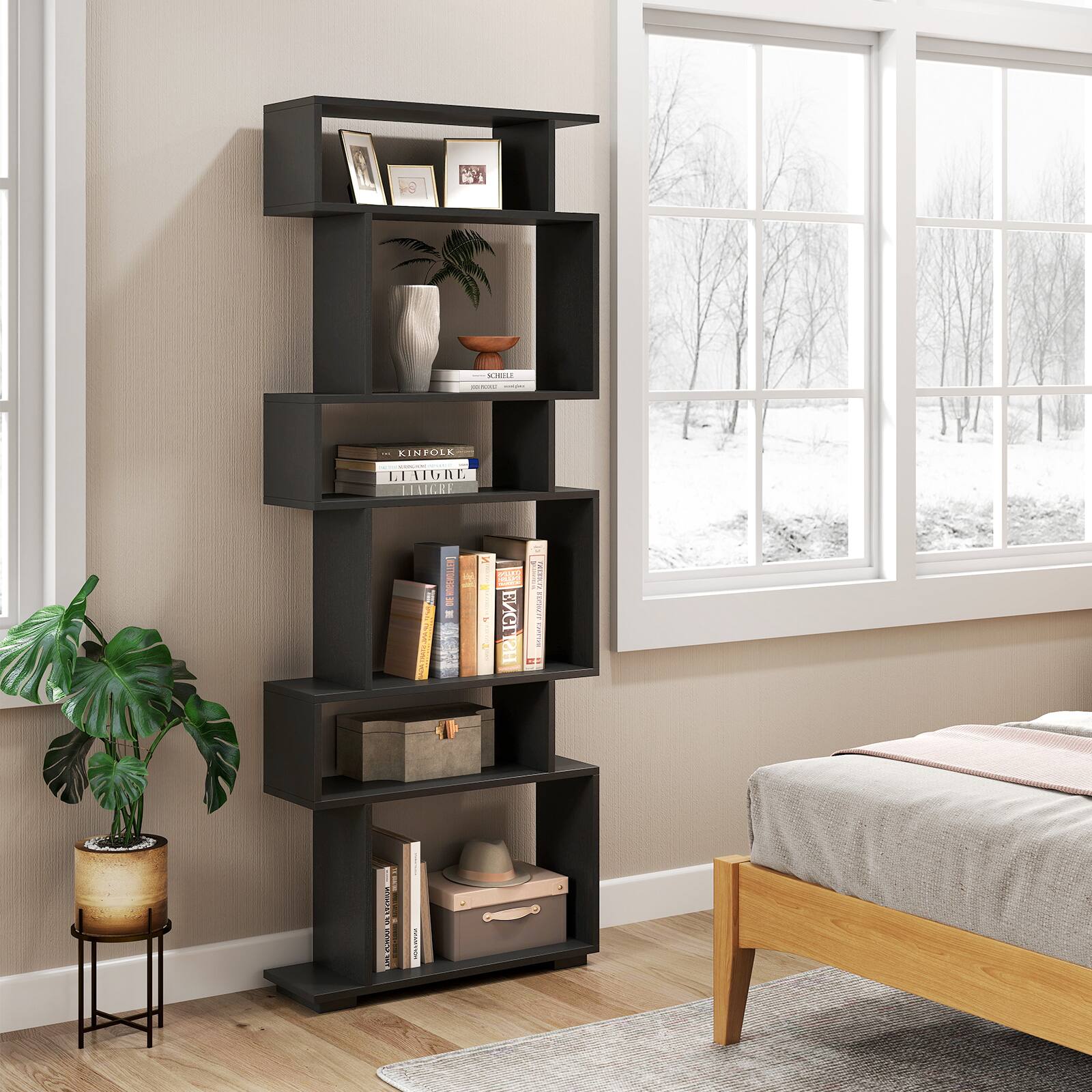 The image shows a room with a bed, a bookshelf, and a window. The bookshelf is filled with books and other items, including a vase and a potted plant. The books are arranged on different shelves, and there is a variety of sizes and colors. The window provides natural light to the room, creating a cozy and inviting atmosphere. The bed is positioned near the window, allowing for a pleasant view while resting. The room appears to be well-organized and comfortable, with the bookshelf serving as a focal point and a source of inspiration for the occupants.