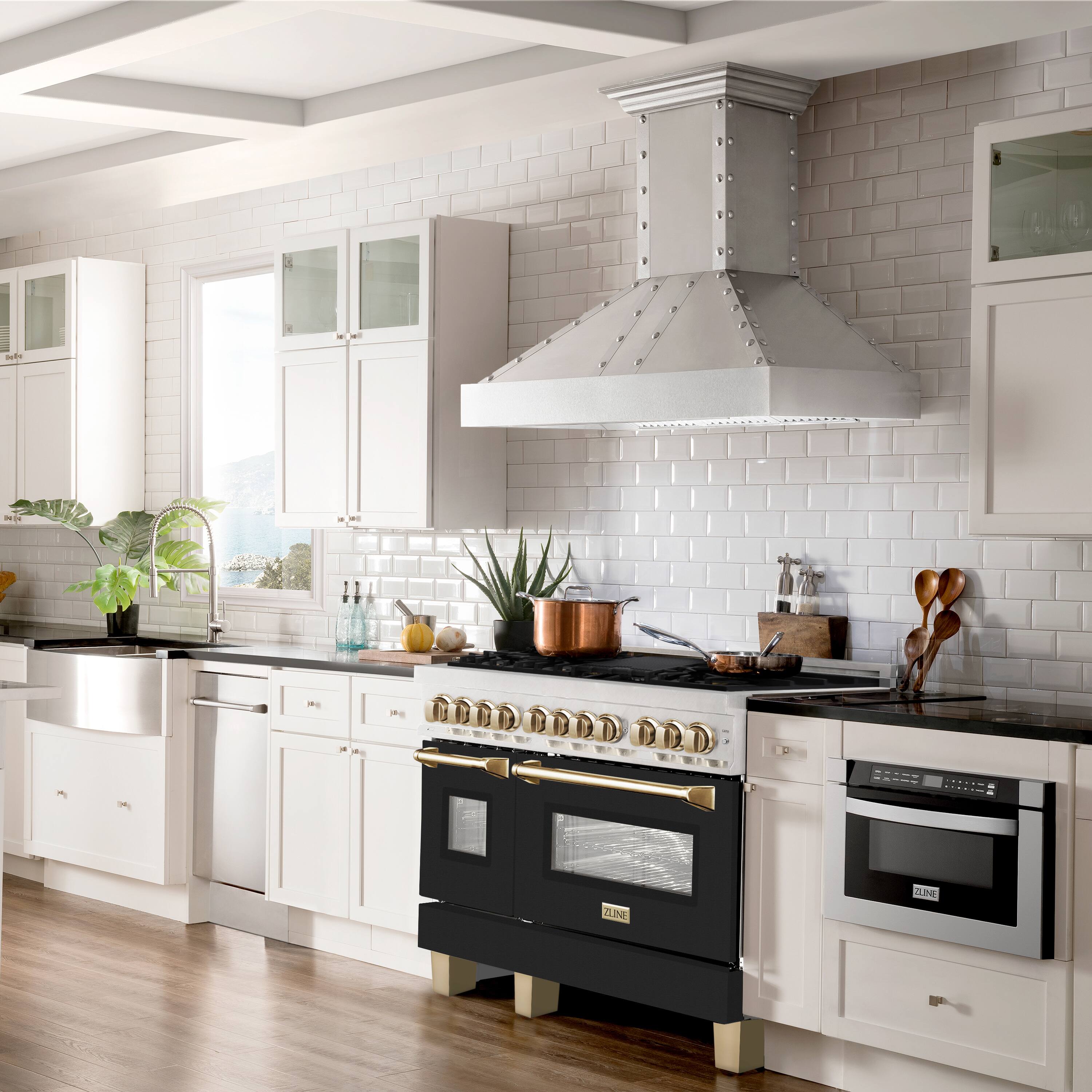 The image shows a kitchen with white cabinets and a black oven. The kitchen is well-equipped with various appliances, including a sink, a refrigerator, and a microwave. There are also several bottles and bowls placed around the kitchen, as well as a potted plant and a vase. The overall design of the kitchen is modern and functional, with a focus on cleanliness and organization.