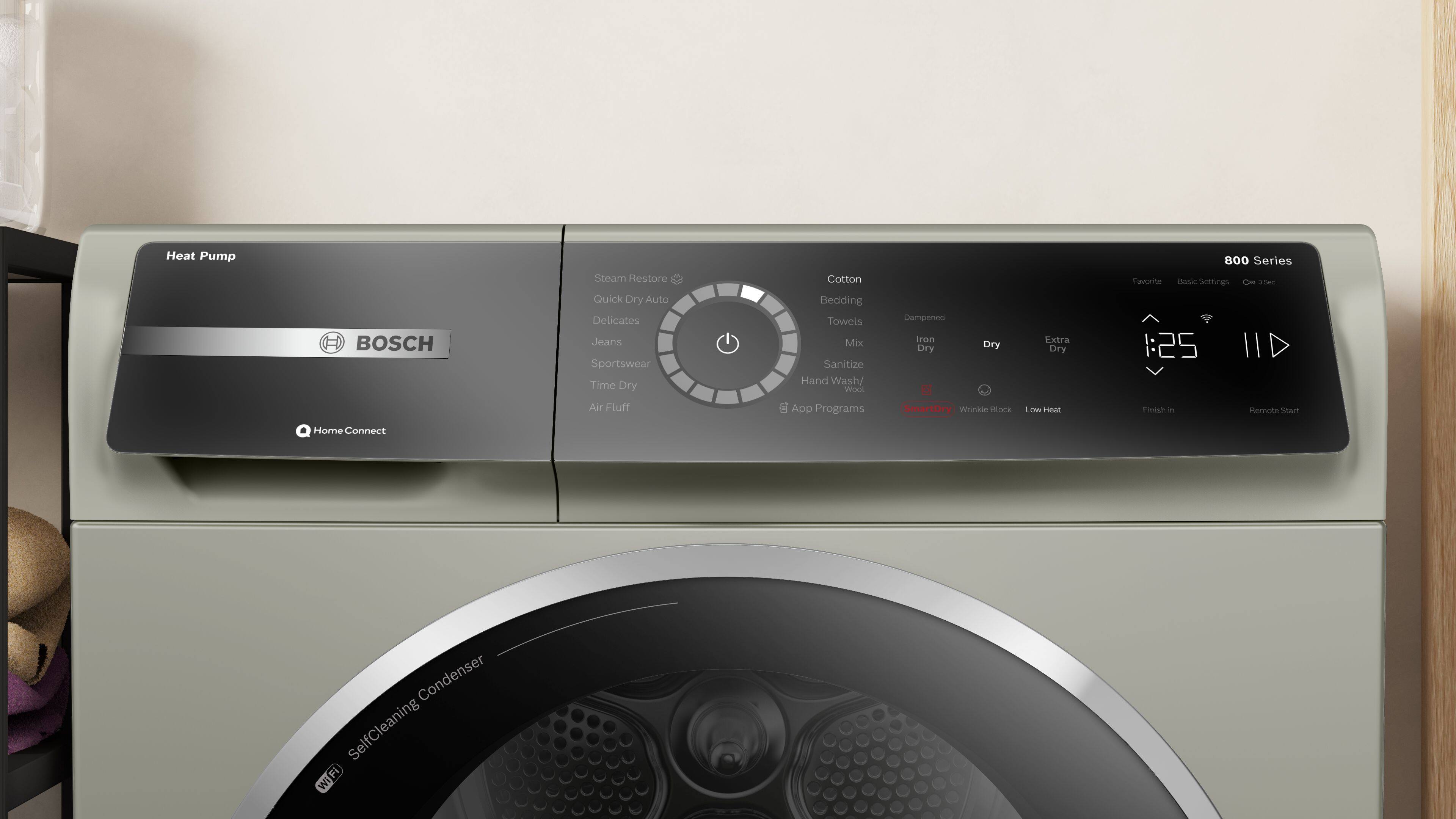 The text on the image is a description of a Bosch washing machine, which is a heat pump machine with various features and settings. It can handle different types of laundry, such as delicates, jeans, sportswear, and cotton bedding. The machine also has a time dry option, as well as a quick dry feature. In addition, it offers various programs, including SmartDry, Wool, and Low Heat Finish. The machine can be controlled remotely through the Home Connect system, and it has a self-cleaning condenser.