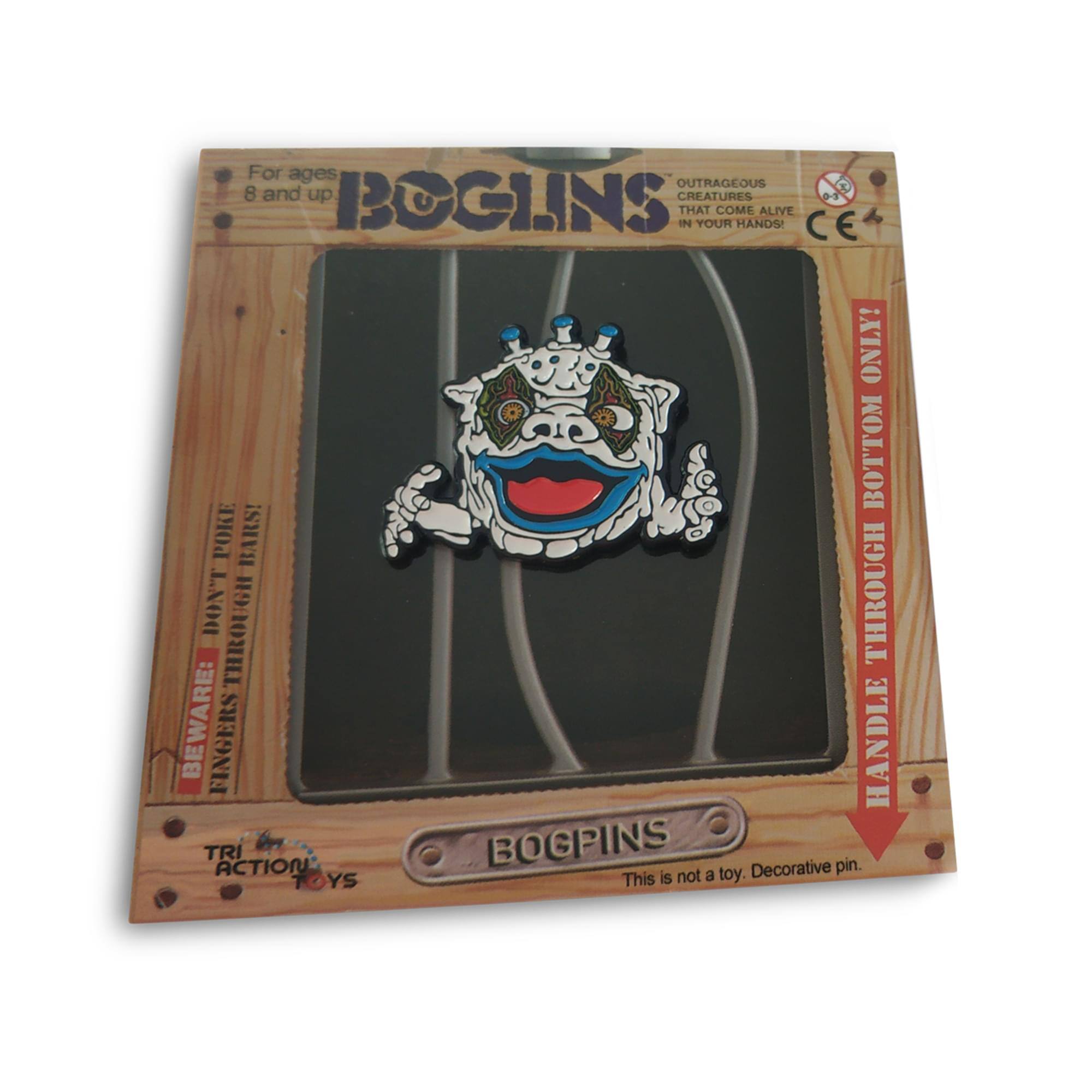 For ages 8 and up  
BOGPINS  
OUTRAGEOUS CREATURES THAT COME ALIVE IN YOUR HANDS!  
BEWARE: FINGERS THROUGH THE BOTTOM THROUGH HANDLE BOGPINS  
This is not a toy. Decorative pin.  
TRI ACTION TOYS