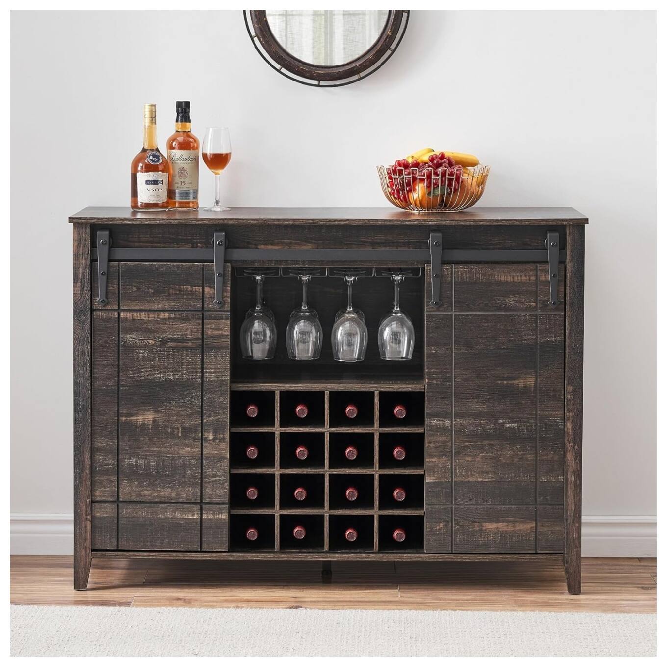 Close up of a wooden wine cabinet with bottles of alcohol and a bowl of fruit on top.