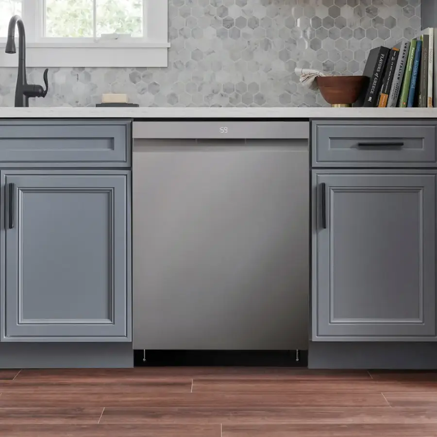 The image features a kitchen with a stainless steel dishwasher and a sink. The dishwasher is located under a counter, and there is a bowl on the counter. The kitchen also has a window, and a book is placed on the counter.
