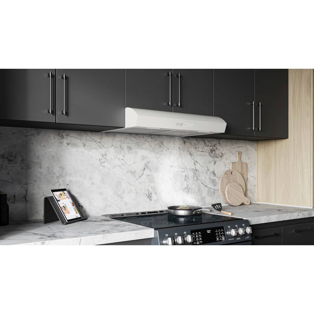 The image shows a kitchen with a stove top oven and a ventilation fan. The stove is in use, with a pan on it, and there is a tablet sitting on the counter next to the stove. The kitchen also features a sink and a spoon, and there is a bowl nearby. The kitchen is equipped with a ventilation fan, which is located above the stove.