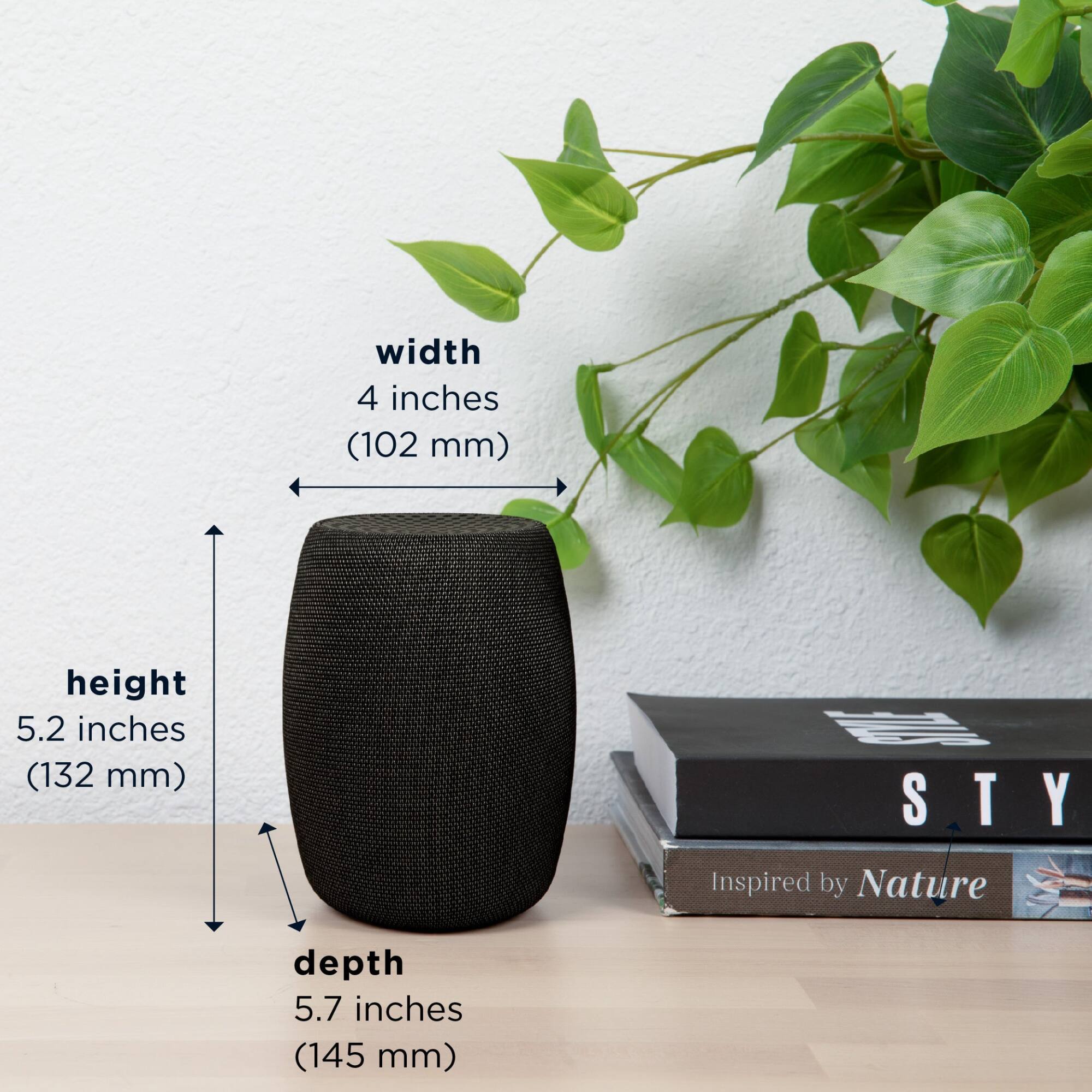 The image shows a black speaker sitting on a table with a plant nearby. The speaker is described as having a width of 4 inches (102 mm), a height of 5.2 inches (132 mm), and a depth of 5.7 inches (145 mm). Additionally, there is a book on the table, which is titled "Inspired by Nature."