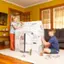 Two children are sitting on the floor, painting a white box that says "Pit Stop" on it.