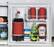 The refrigerator is filled with various food items, including a bottle of Coca-Cola, a bottle of ketchup, a bottle of mayonnaise, and a bottle of sriracha. The refrigerator is small and has a red interior.