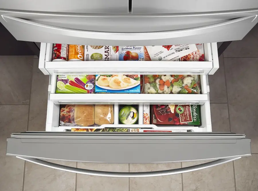 The image shows an open refrigerator with various food items inside. There are several bottles, including a bottle of coconut water, and a container of yogurt. The refrigerator also contains a bowl and a carrot. The refrigerator is filled with a variety of food items, making it a well-stocked kitchen.