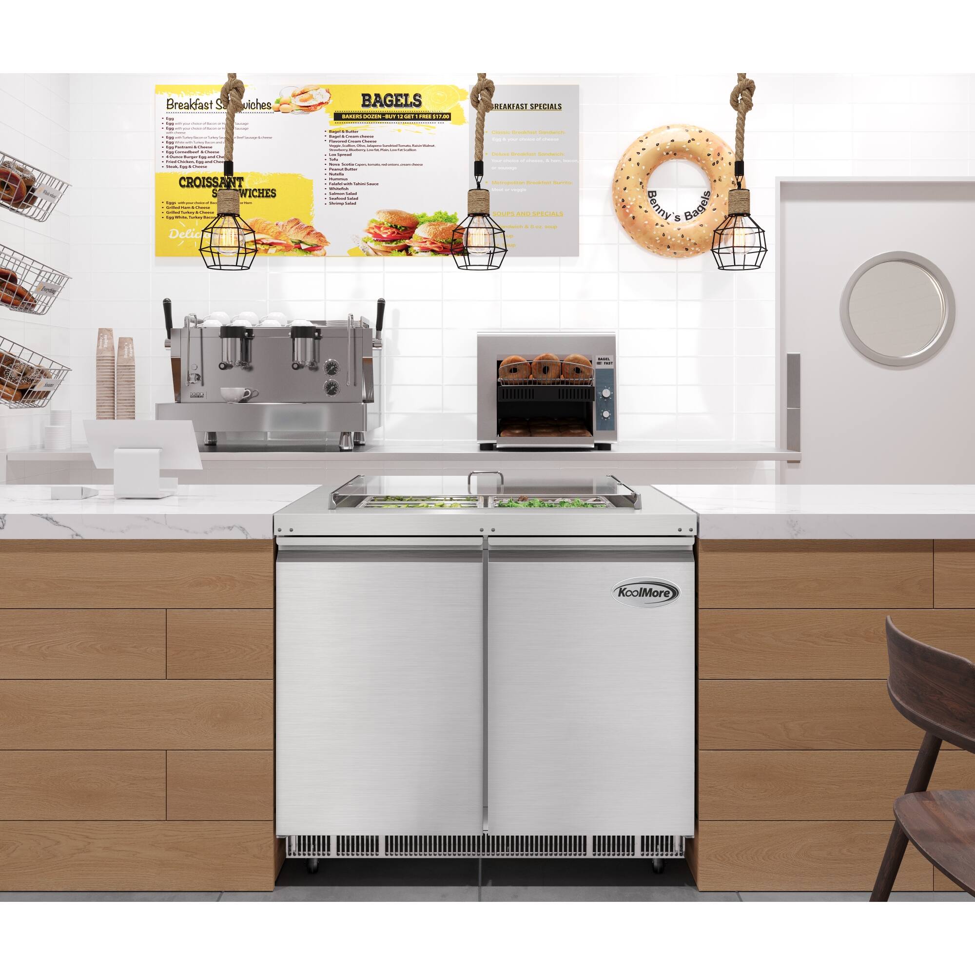 Breakfast sandwiches, bagels, croissants, and wiches are available at this establishment. The image features a kitchen with a metal refrigerator, a doughnut machine, and a sink. There is also a dining table with a chair nearby.