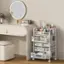 The image shows a bathroom vanity with a mirror above it. The vanity has a white countertop and is accompanied by a white stool. On the countertop, there are various items such as a tray of makeup, a vase, and a bottle. Additionally, there are two cups placed nearby. The overall scene is clean and organized, with the vanity and stool taking up a significant portion of the image.