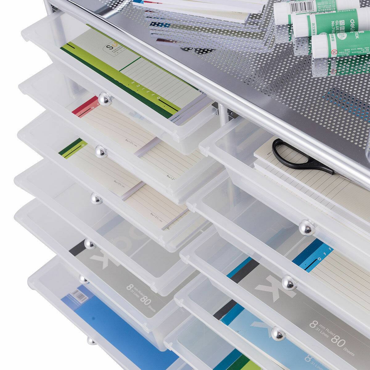 The image features a white plastic container with various items inside, including notebooks, pens, and glue sticks. There are multiple notebooks in different sizes and colors, as well as several pens and pencils. The container also contains a pair of scissors and a pair of glasses. The items are neatly organized in the container, making it a practical storage solution for office supplies.