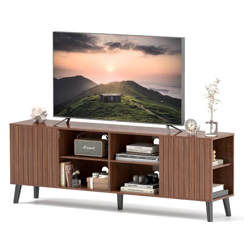The image features a large flat-screen TV sitting on top of a wooden entertainment center. The TV is displaying a beautiful sunset scene. The entertainment center has a clock on it, and there are several books placed nearby. Additionally, there is a vase and a potted plant in the scene, adding to the overall aesthetic of the space.