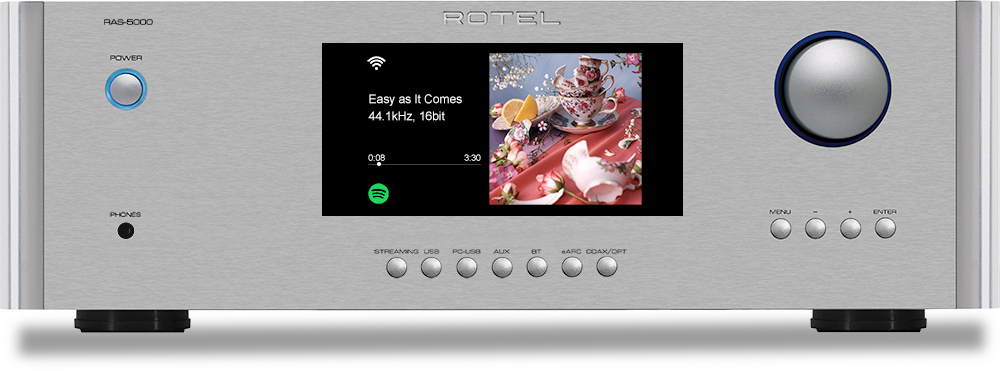 The text on the image reads: "RAS-5000 ROTEL POWER Easy as It Comes 44.1kHz, 16bit 0:08 3:30 PHONES MENU ENTER STREAMING USB PC-USB AUX BT SAPC COAX/DPT." This text describes the features and capabilities of the electronic device, which is a stereo system. The device has a USB connection for streaming, a PC-USB connection, an AUX connection, Bluetooth connectivity, and a coaxial/digital connection. The device also has a menu and enter button for user interaction.