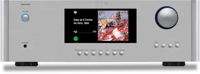 The text on the image reads: "RAS-5000 ROTEL POWER Easy as It Comes 44.1kHz, 16bit 0:08 3:30 PHONES MENU ENTER STREAMING USB PC-USB AUX BT SAPC COAX/DPT." This text describes the features and capabilities of the electronic device, which is a stereo system. The device has a USB connection for streaming, a PC-USB connection, an AUX connection, Bluetooth connectivity, and a coaxial/digital connection. The device also has a menu and enter button for user interaction.