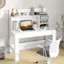 A white desk with a laptop, mouse, and books on it. A chair is placed in front of the desk.