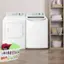 The image features a laundry room with two white washing machines and a dryer. The washing machines are placed next to each other, and the dryer is situated nearby. There is also a basket of laundry in the room, containing various items such as towels and clothes. The laundry room is well-organized, with the machines and dryer neatly arranged, making it an efficient space for doing laundry.