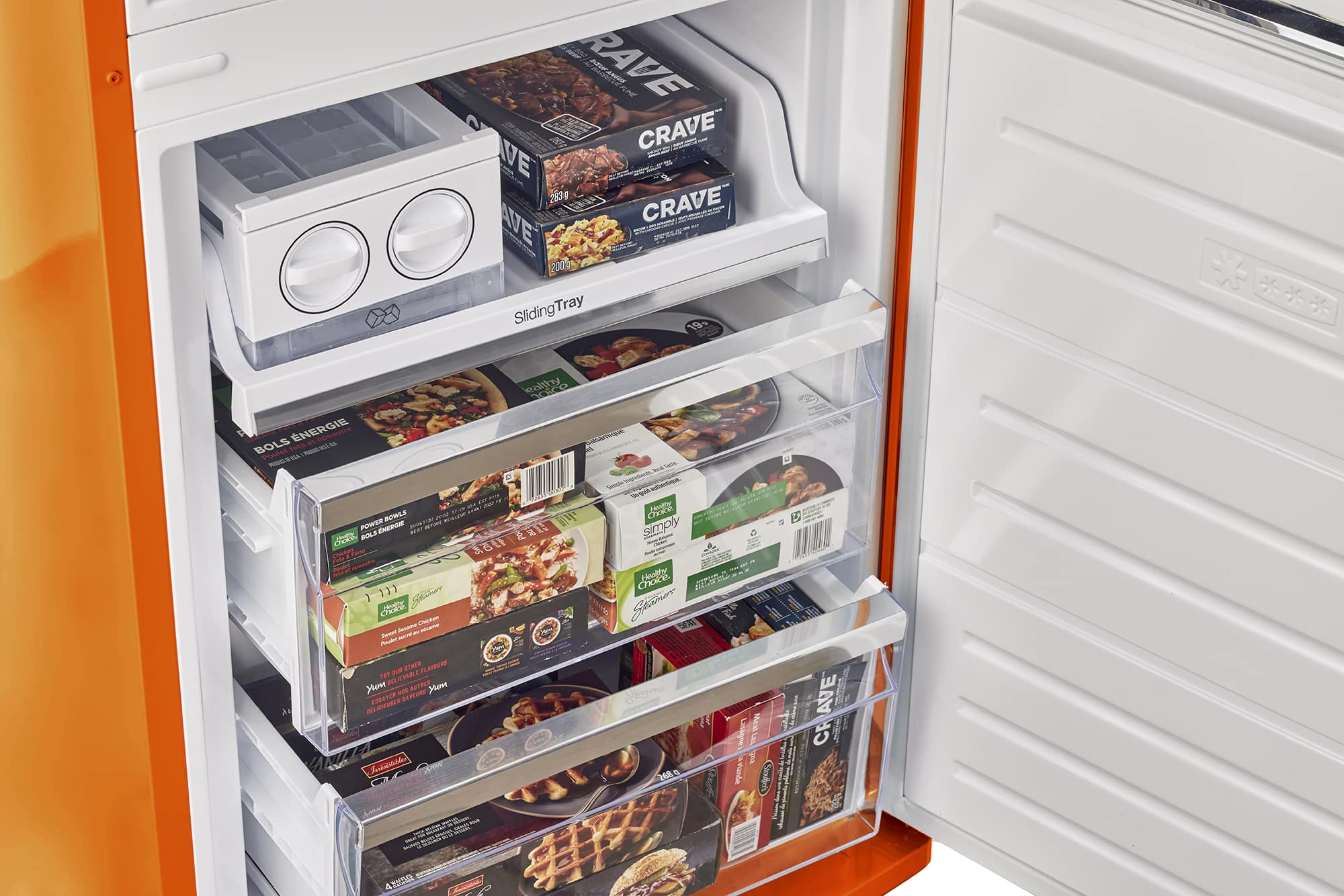 The image shows a refrigerator with its door open, revealing a variety of food items stored inside. There are several boxes of food, including Crave and other brands, placed in the refrigerator. The refrigerator is filled with food, and the door is open, allowing a clear view of the items inside.
