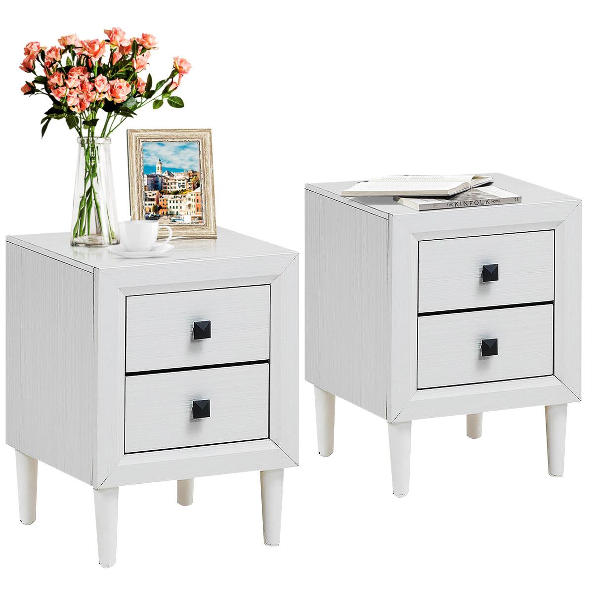 The image features two white dressers, each with a drawer and a cup on top. One dresser has a vase of flowers and a picture frame on it, while the other dresser has a book on top. The dressers are placed next to each other, creating a symmetrical and visually appealing arrangement.