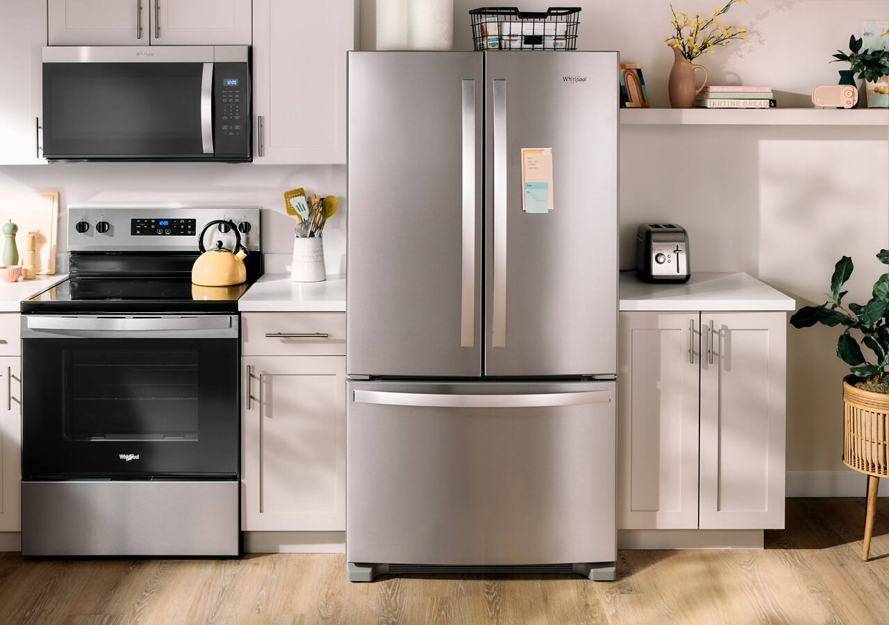 The image shows a kitchen with a stainless steel refrigerator, a stove, and a microwave. The refrigerator is located next to the stove and microwave, which are both black. The kitchen also features a sink and a potted plant. The refrigerator is a large, modern appliance that adds a touch of elegance and functionality to the space.