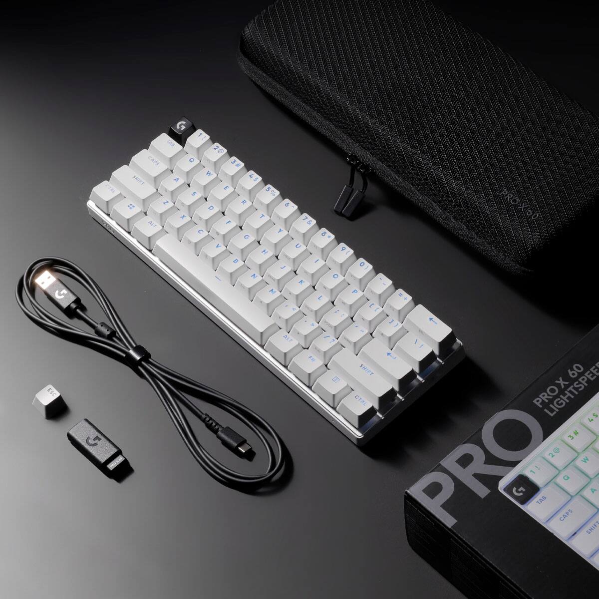 The image features a white keyboard and a black case, with the keyboard sitting on top of the case. The keyboard is accompanied by a black cord, and there is a black case next to it. The keyboard has a USB plug attached to it, and it is placed on a black surface.