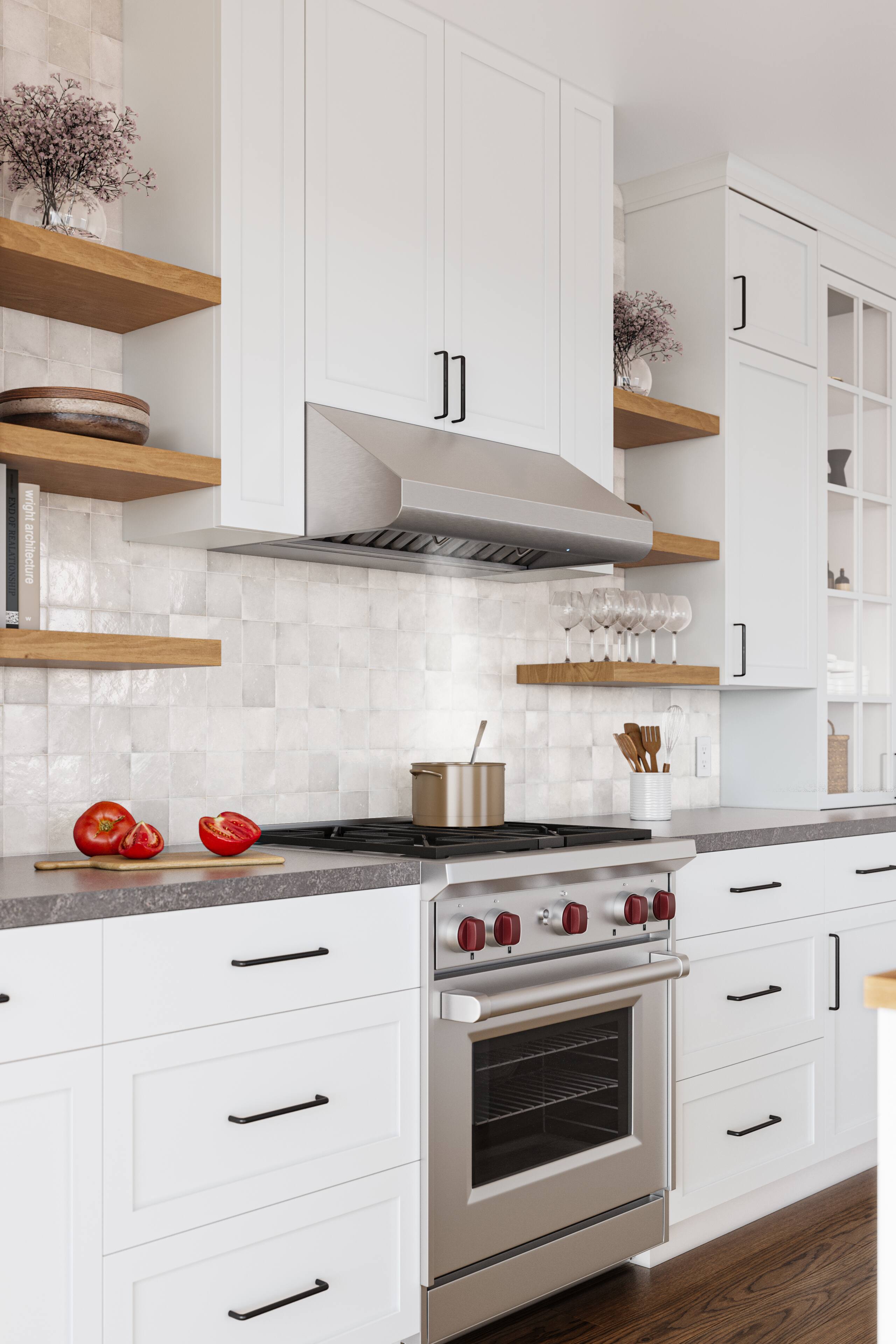The image features a kitchen with white cabinets and a stove top oven. The kitchen is well-equipped with various items, such as a bowl, a spoon, a knife, and a couple of bottles. There are also some apples and oranges on the countertop. The kitchen has a clean and organized appearance, with a vase placed on a shelf, adding a decorative touch to the space.