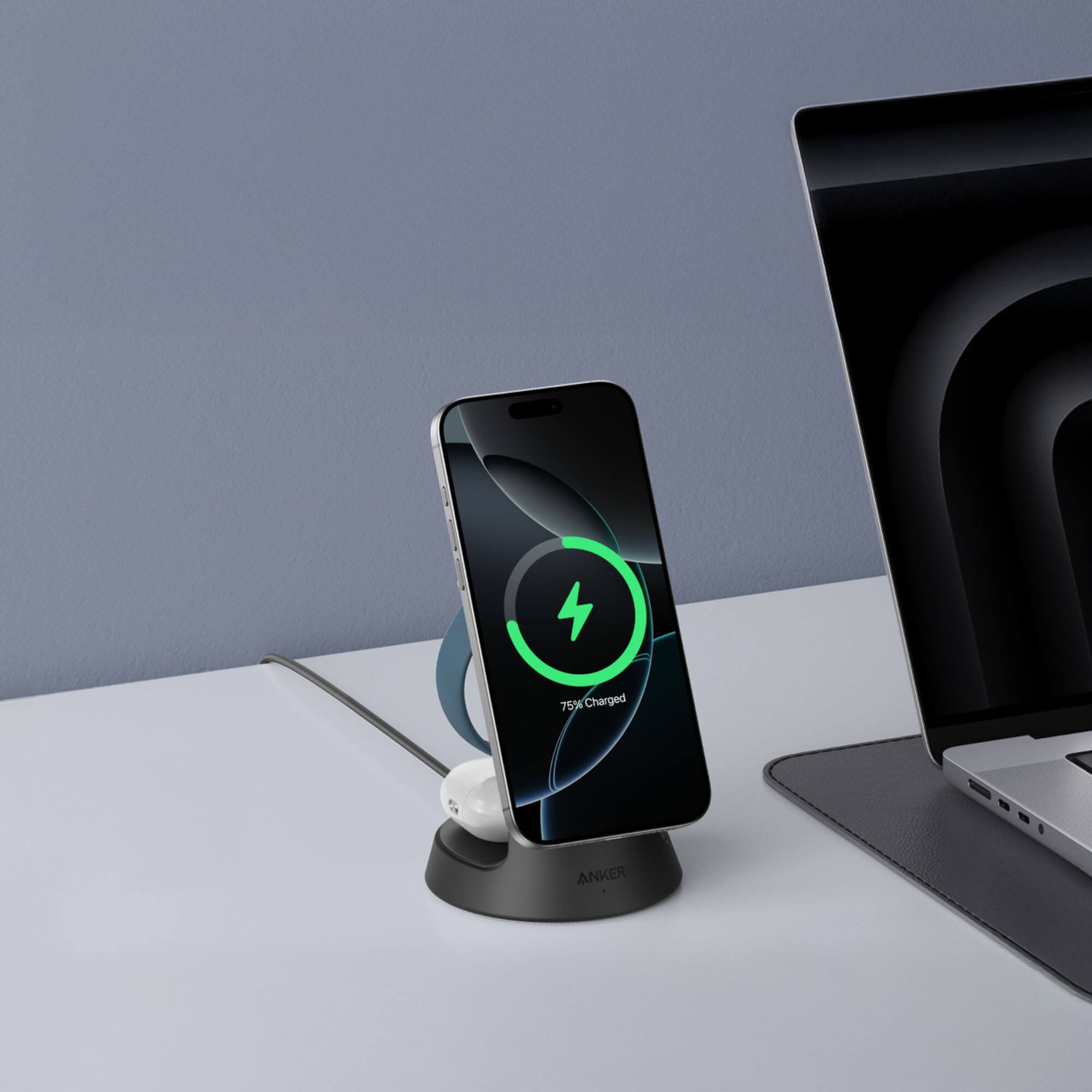 The image shows a cell phone and a laptop on a table. The cell phone is 75% charged and is placed on a charging stand. The laptop is open and ready for use. The scene suggests that the user might be working or studying, utilizing both devices for their tasks.