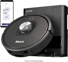 The image features a black robotic vacuum cleaner, which is a Shark Mattrx. The vacuum is sitting next to a cell phone, which is sold separately. The robotic vacuum is designed to clean and maintain the cleanliness of the floor.